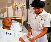 Nurse giving IV drug to cancer patient