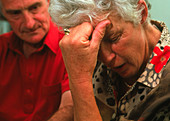Depressed elderly woman with partner looking on