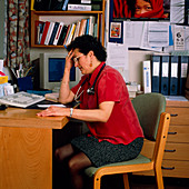 Stressed female GP doctor working at her desk
