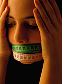 Teenage girl with tape measures over her mouth