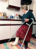 Woman with broken leg and crutches makes tea