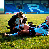 Physiotherapist examining player's injured knee
