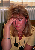 Sunburnt woman with a headache holding her head