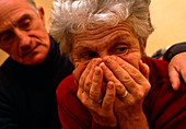 Upset elderly woman comforted by elderly man