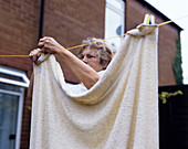 Elderly woman hanging washing