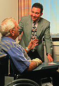 Elderly disabled man in wheelchair with doctor