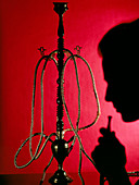 Silhouetted man smoking cannabis from a pipe