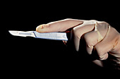 Surgeon wearing rubber gloves,holding scalpel