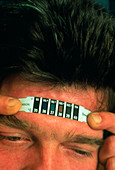 Man using a thermochromic strip thermometer