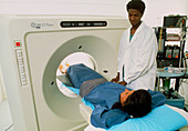 Female radiologist moves patient into a CT scanner