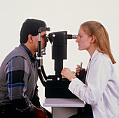 Optician examining man's eyes