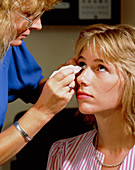 Optician removing foreign body from eye