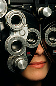 Eye examination: woman looks through a refractor
