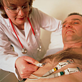 Doctor puts electrodes on man's chest for ECG test