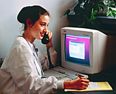 Female doctor by computer using telephone