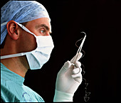 Profile of masked surgeon holding suture