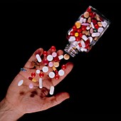 Bottle of assorted pills tipped into a hand