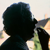 Silhouette of an elderly woman taking an aspirin