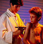 Doctor uses a vaccine gun to inject a young boy