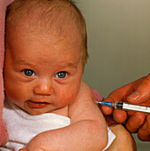 Doctor's hand injecting or vaccinating baby's arm