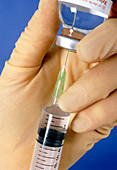 Gloved hand drawing an injection into a syringe