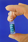 Gloved fingers hold an ampoule of tetanus vaccine