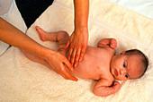 Hands carry out physiotherapy on baby's abdomen