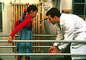 Physiotherapist helping a young girl to walk