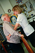 Physiotherapist helping an elderly man stand