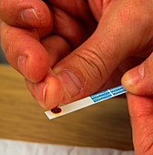 Man dips blood from finger onto glucose test strip