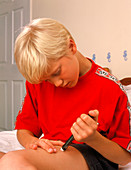 Teenage boy self-injecting with insulin novopen