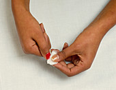 Woman removing red nail varnish from fingernails