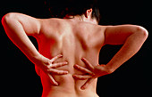 Woman suffering from back pain doing self-massage