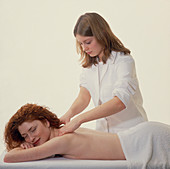 Masseuse massages the neck & shoulders of a woman