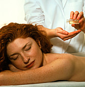Masseuse pours oil before massaging a woman