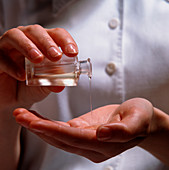Aromatherapy oil being poured into a cupped hand