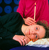 Woman being treated with a Hopi ear candle