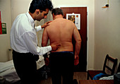 Osteopath examines the lower spine of a man