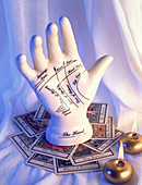Model palmistry hand with tarot cards and candles