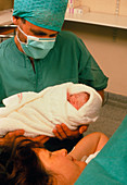 Mum happily looking at her newborn baby