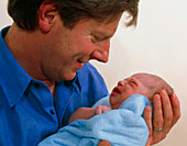 Father cradles his newborn baby boy