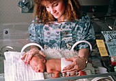 Nurse handling baby in incubator