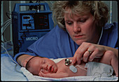 Neonatal baby in intensive care monitored by nurse