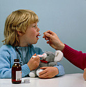 Child receiving a dose of cough mixture