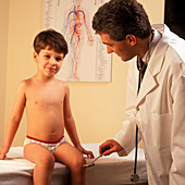 Doctor tests the knee jerk reflex of a young boy