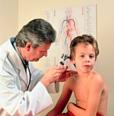 Paediatric doctor examines the ear of a young boy