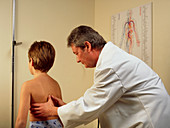 Doctor examining the spine/chest of a young boy