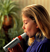 Lung function: girl breathes into peak flow meter