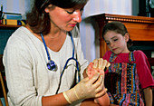 Doctor examines verruca on foot of young girl