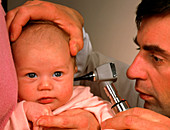 Doctor examining ear of baby girl with an otoscope